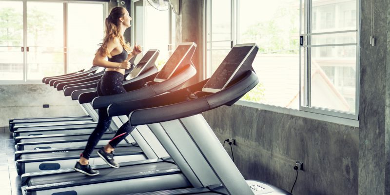 Cute young woman exercising on  treadmill at a gym.Active young woman running on treadmill. smile and funny emotion.